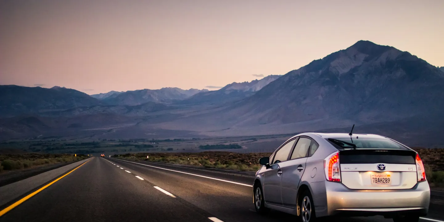 Silver hybrid car on an open highway toward the mountains
