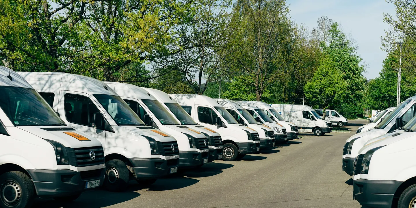 Row of white cargo vans parked in a lot