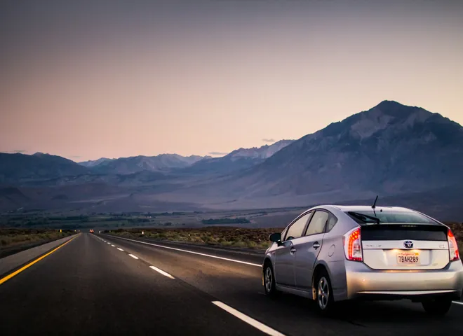 Silver hybrid car on an open highway toward the mountains