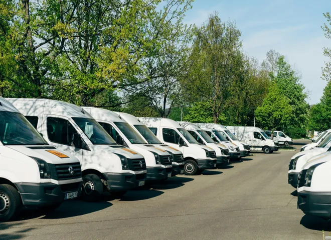 Row of white cargo vans parked in a lot